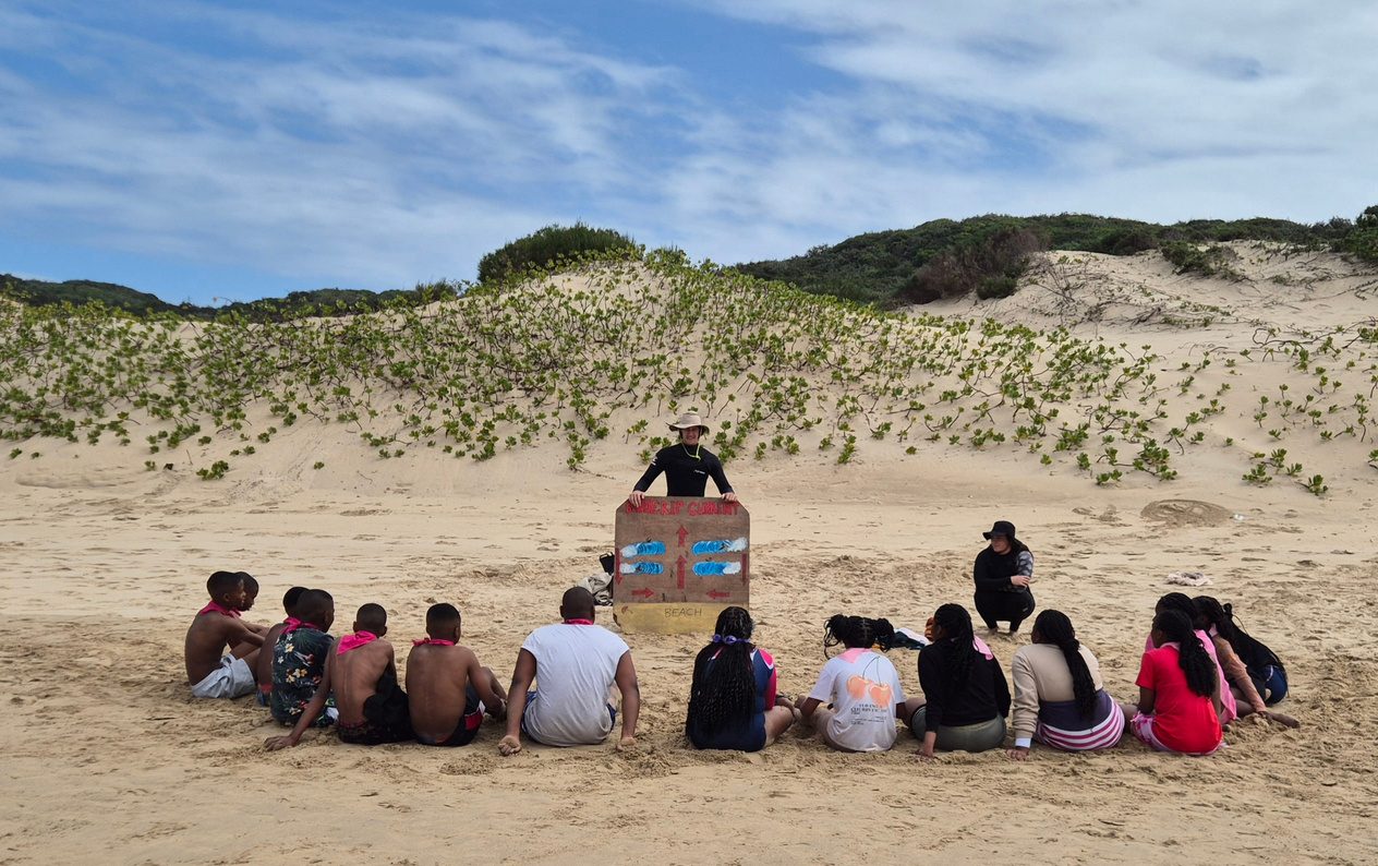 Learners seated on the beach for a rip current safety lesson