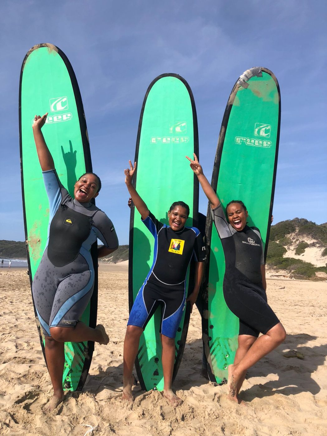 Three surf students celebrating with their boards