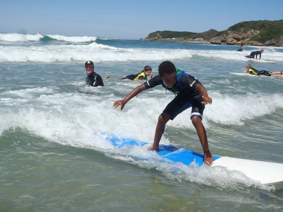 A learner standing up on a surfboard at Nahoon Beach