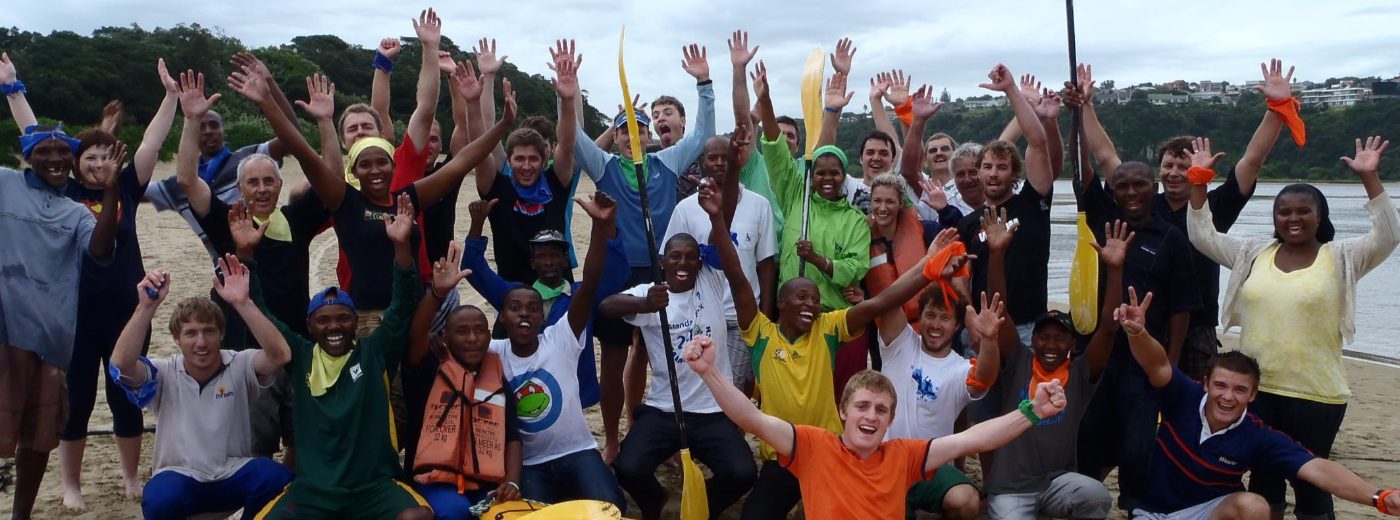 A corporate team cheering on the beach after canoeing